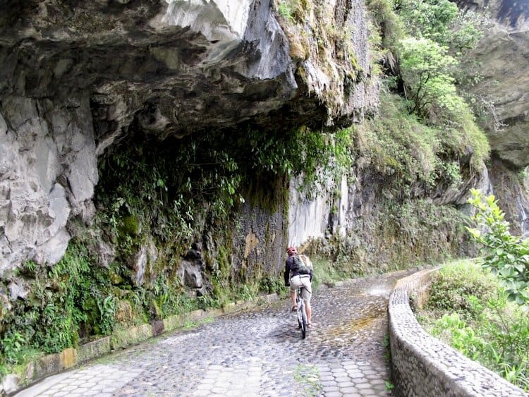 Man riding bike on cobblestone road on Ruta de las Cascadas in Ecuador