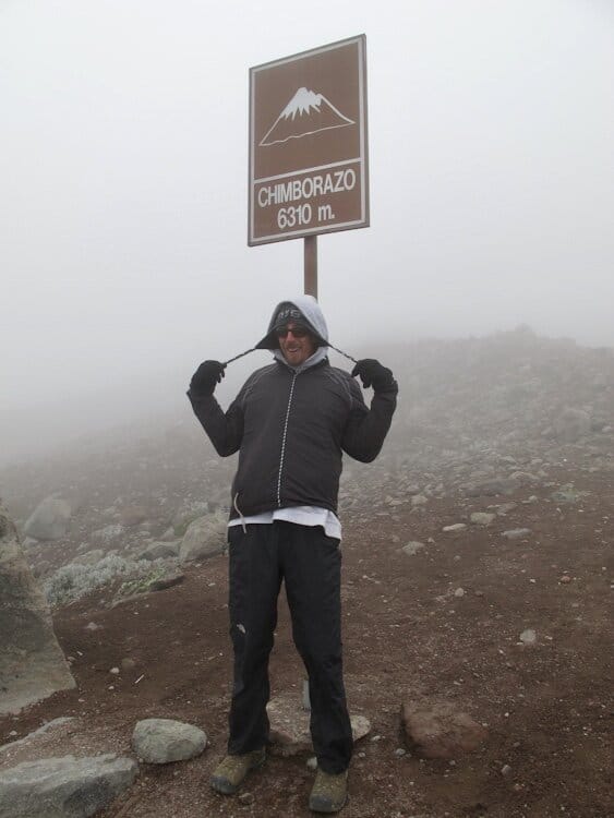 Man standing next to sign that says "Chimborazo 6310 m" in Ecuador