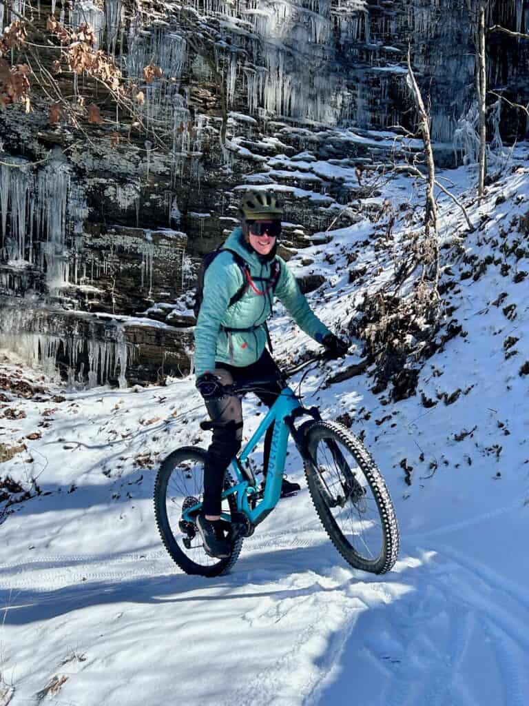 Woman mountain biking on snowy trail