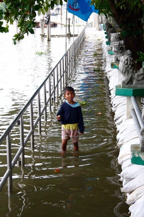 Boy standing in flooded walkway in Thailand