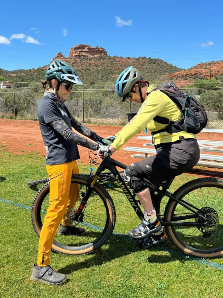 Female mountain bike coach holding handlebars of student