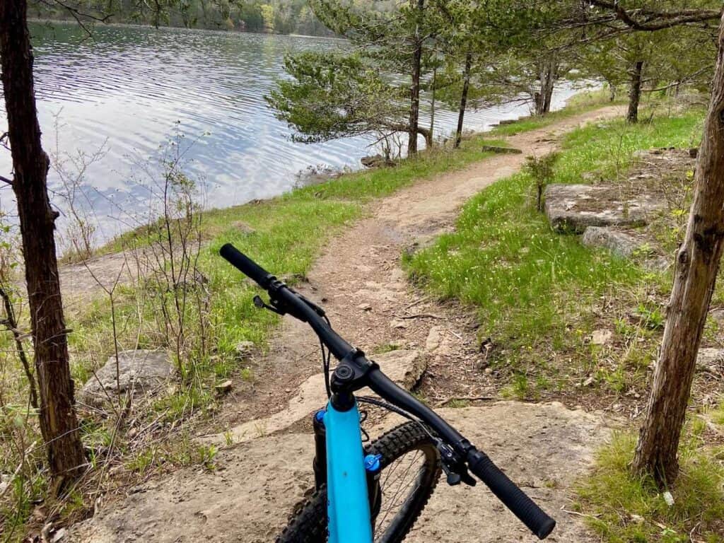 Photo out over handlebars of mountain bike onto singletrack Lake Leatherwood trail in Arkansas