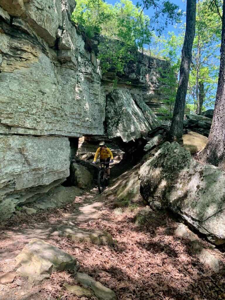 Pengendara sepeda gunung mengendarai sepeda melewati gua batu di jalur Devil's Racetrack di Devil's Den State Park