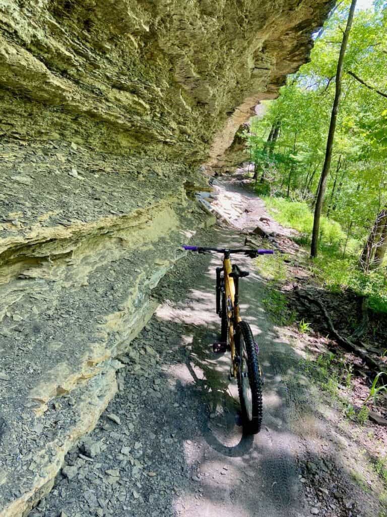 Mountain bike propped up against limestone cliff wall overhang on trail in Devil's Den State Park in Arkansas
