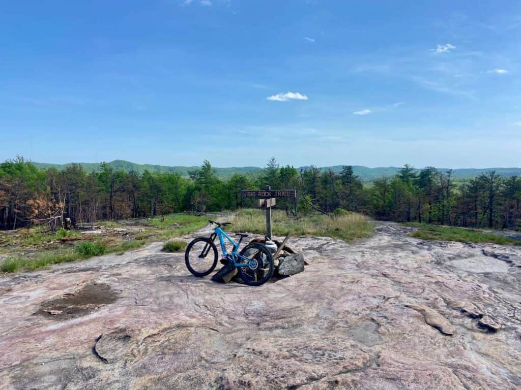 Mountain bike leaning against trail sign at rock slab summit in DuPont State Forest in North Carolina