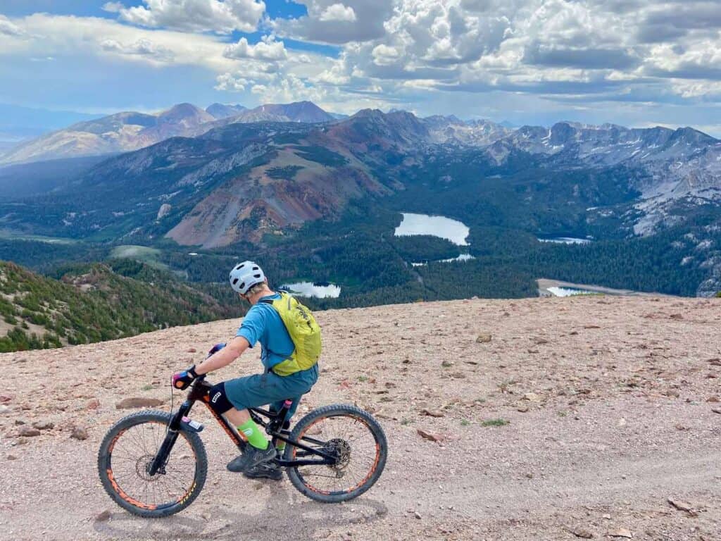 Man stopped on mountain bike at top of Mammoth Mountain Bike Park looking out over mountainous landscape views