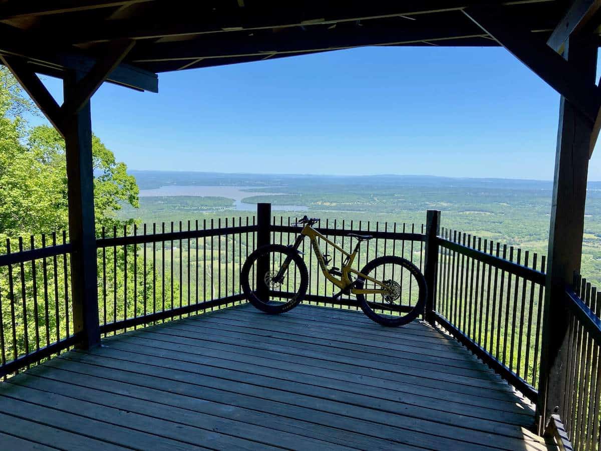 Silhouette of mountain bike leaning against railing under gazebo with expansive landscape views in background in Arkansas