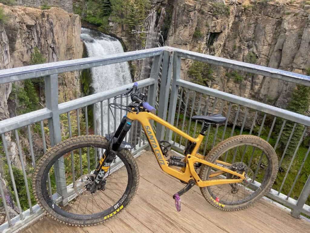 Mountain bike propped up against railing with waterfall behind at Tumalo Falls in Oregon