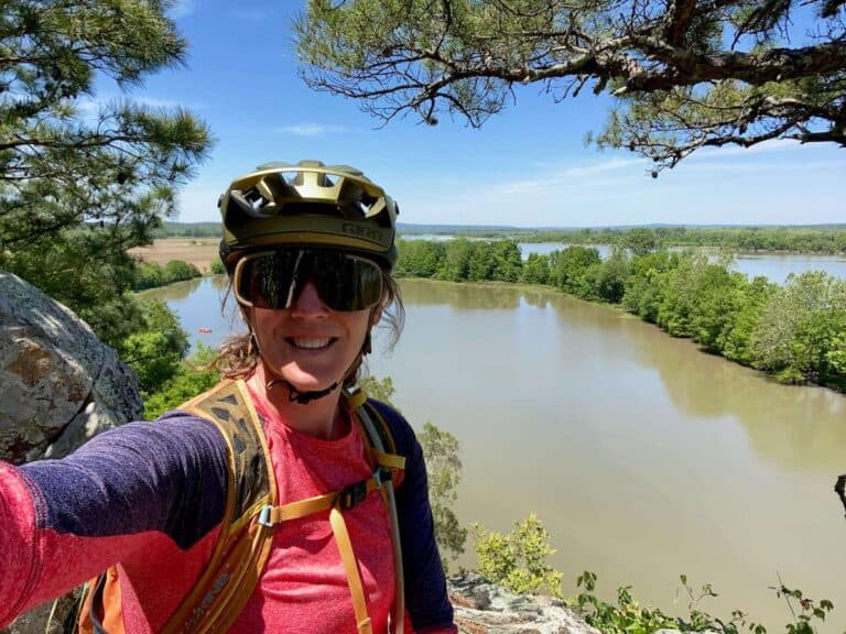 Woman taking a selfie at lookout point in Pinnacle Mountain State Park in Arkansas. She is wearing a mountain bike helmet and sunglasses