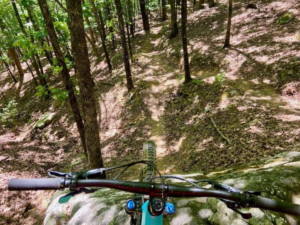 Photo out over front of handlebars of bike down a very steep rock roller at Pinnacle Mountain State Park in Arkansas