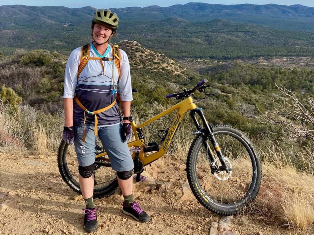 Becky smiling for photo next to mountain bike at desert overlook wearing Giro Manifest helmet