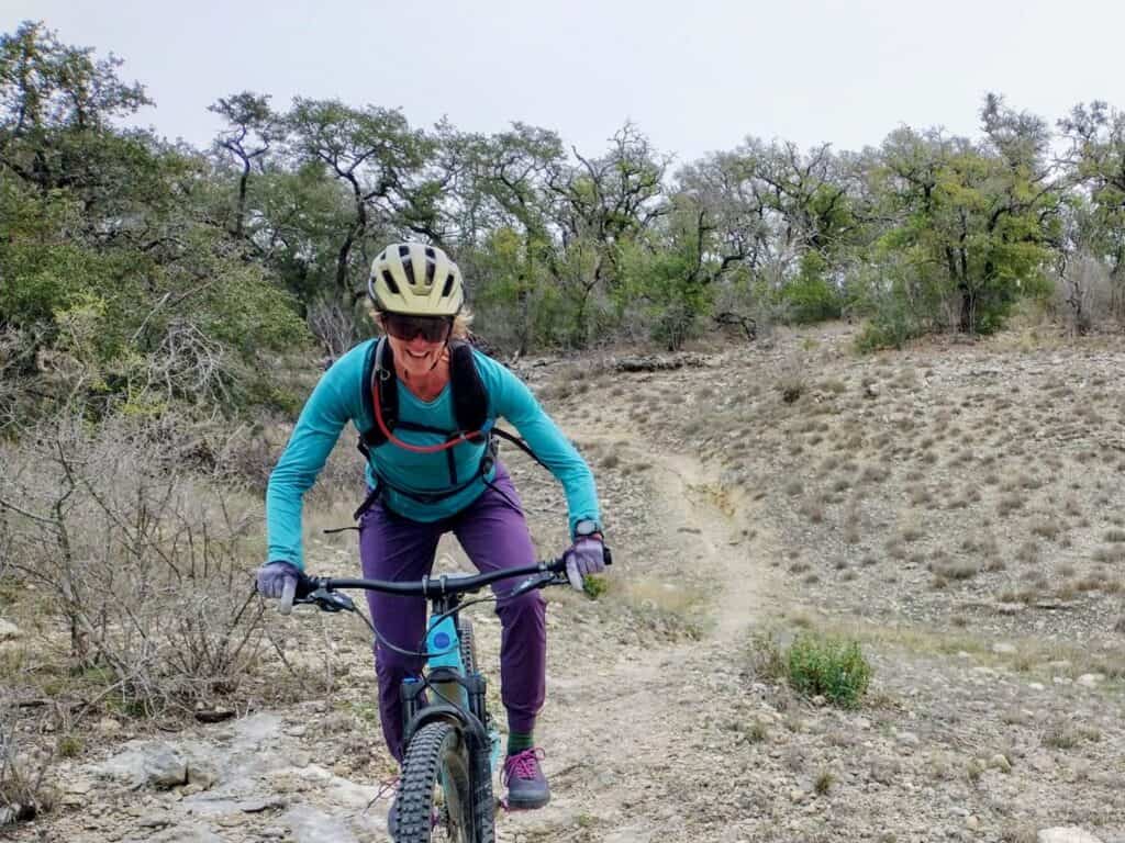 Woman riding mountain bike on trail wearing Giro Manifest Spherical helmet