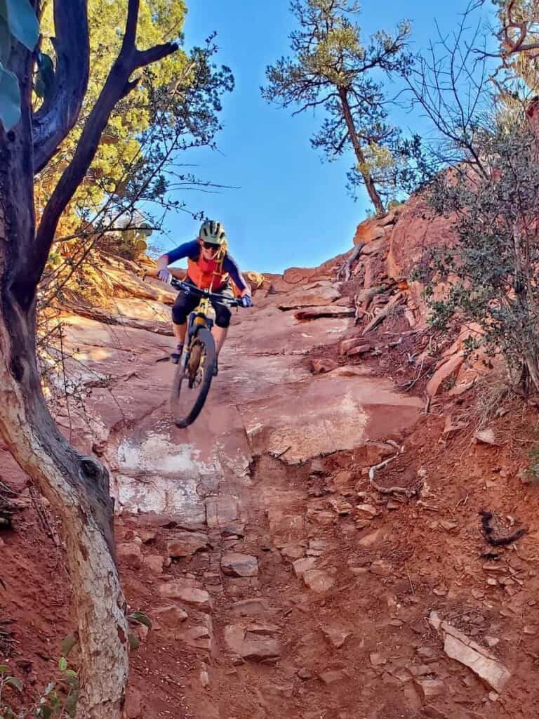 Mountain biker riding down steep red rock chute on Hiline Trail in Sedona