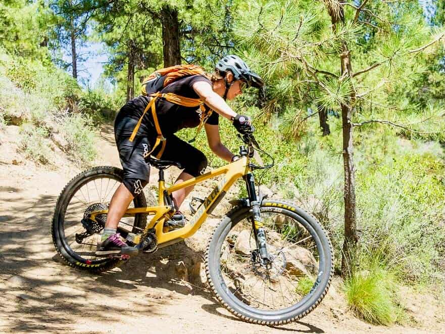 Woman riding mountain bike around corner wearing mountain biking gear