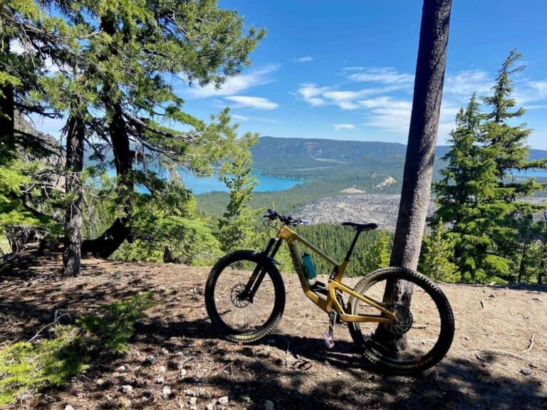 Mountain bike propped up against tree on side of trail near Bend Oregon with blue lake in distance