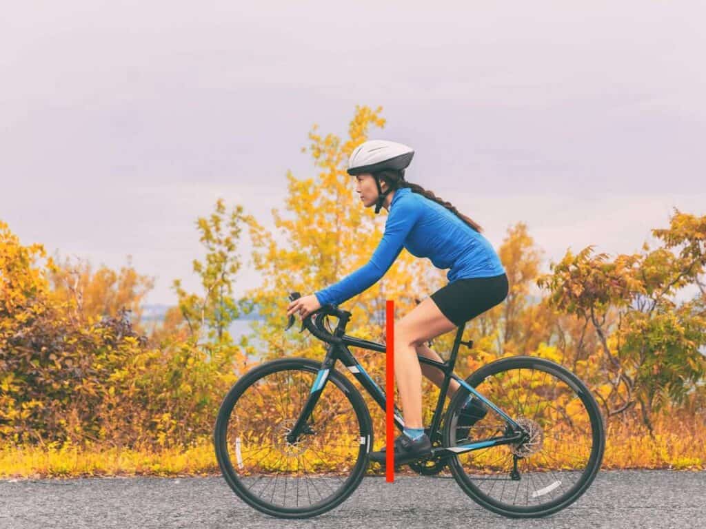 Woman riding bike with overlay red line showing straight line down from knee to pedal for correct bike saddle fore/aft position