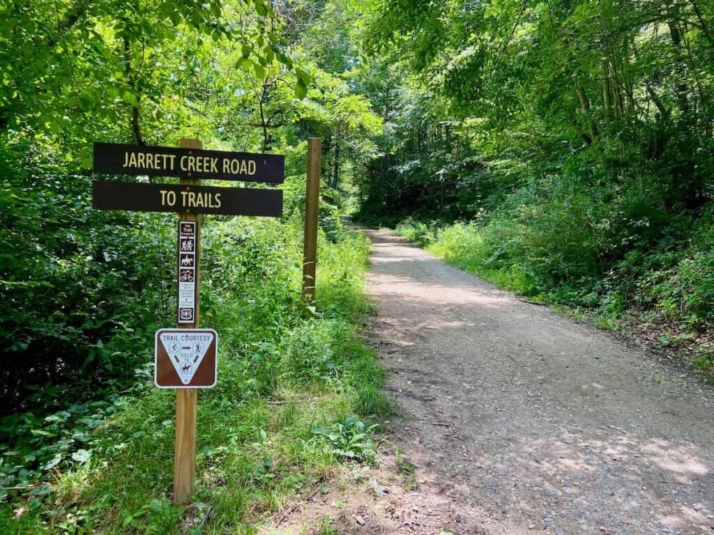 Trail sign next to dirt road at Old Fort Gateway Trails that says "Jarrett Creek Road to Trails"