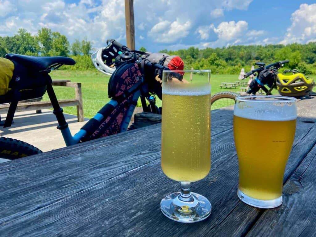 two cold beers on picnic table at Fonta Flora brewery in North Carolina with two bikes in background