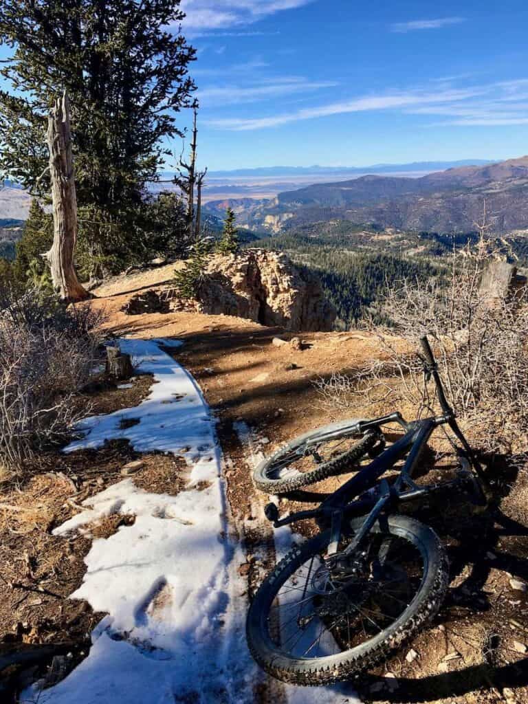 Mountain bike lying next to trail with patches of snow. Views out over Utah's canyonlands