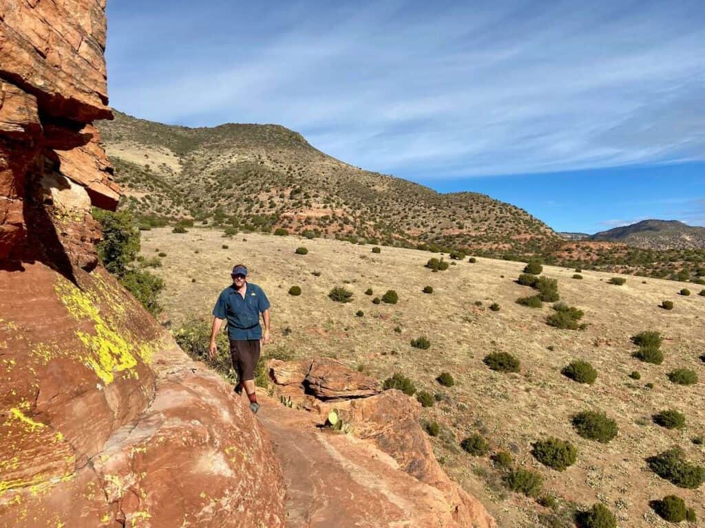 Man walking on narrow rock ledge on rock formation outside of Sedona Arizona