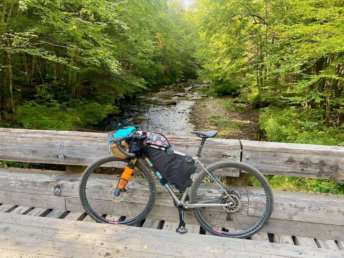 Biking loaded with bikepacking leaning against wooden side of bridge on the VTXL bikepacking route in Vermont