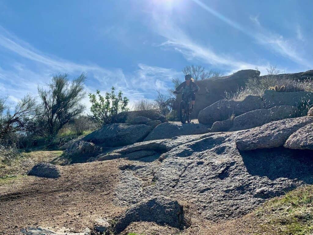 Mountain biker riding bike down rock slab on trail in Phoenix, Arizona