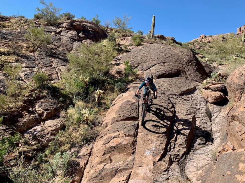 Mountain biker riding down steep rock slab in Arizona