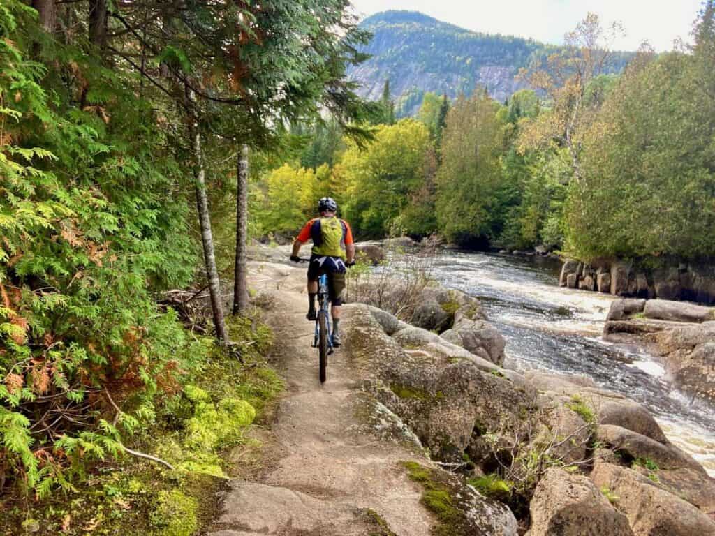 Mountain biker riding bike on rock slabs next to river in Quebec