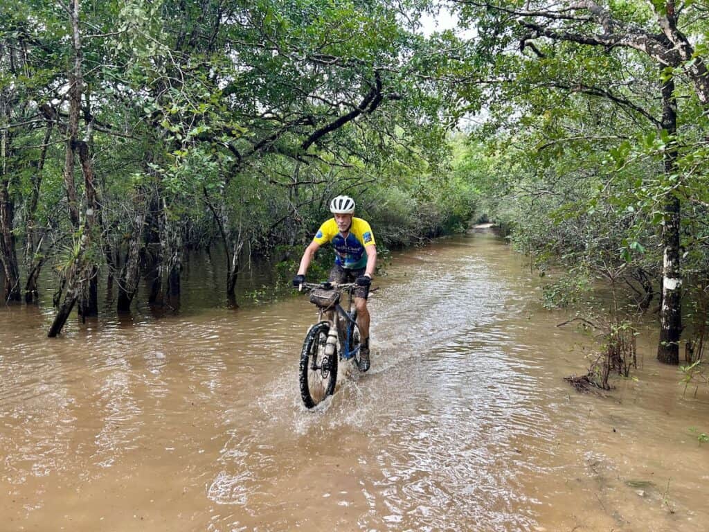 Man riding bike through flooded section of road through the jungle in Mexico