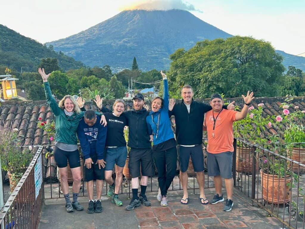 Group of friends in a line for a photo on balcony in front of a volcano