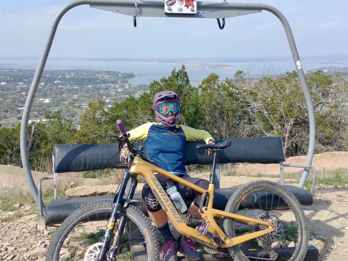 Woman sitting on chairlift with mountain bike at Spider Mountain Bike Park in Texas