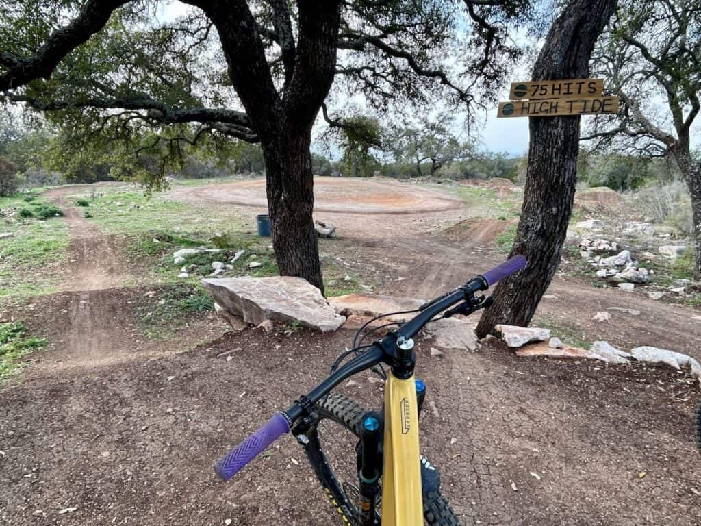 Photo out over mountain bike handlebars onto drop in of jump line at Station Mountain Bike Park in Texas