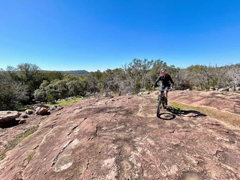 Mountain biker riding bike on granite rock slab at Reveille Peak Ranch in Texas