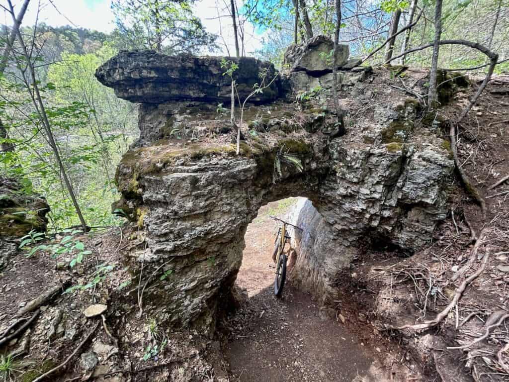 Mountain bike propped up under natural rock arch on trail in Arkansas