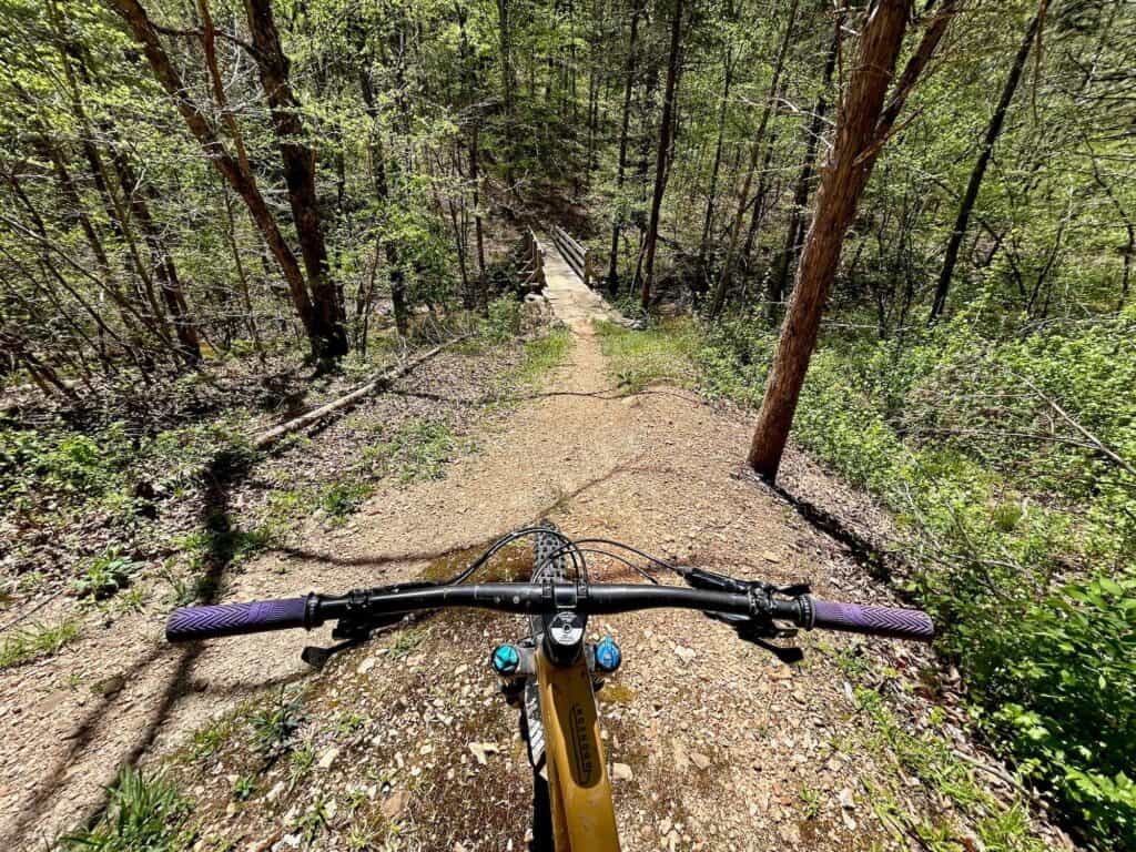 Photo out over front of mountain bike handlbars onto large rock drop at the BOC Ponca downhill trails