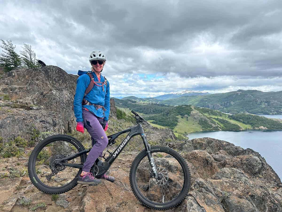 a woman standing over a mountain bike at scenic lookout