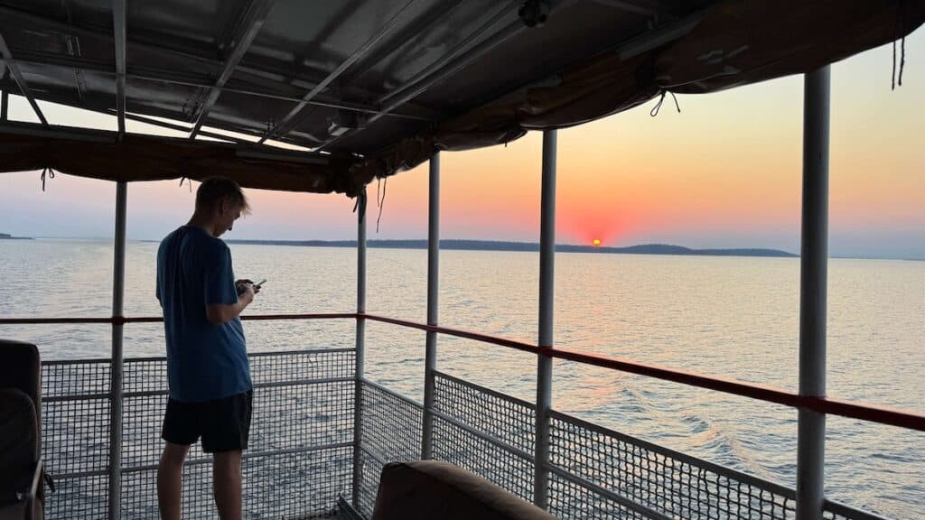 Man standing on deck of ferry at sunrise